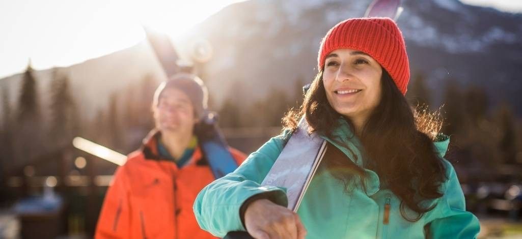 Woman carrying skis in spring sunlight