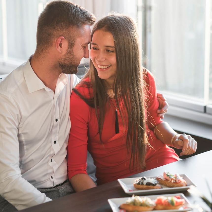 Pareja sonríe muy junta ante platos de bruschetta en una mesa de restaurante de Megapolis Hotel Panama