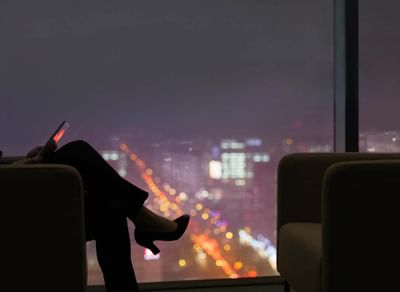 femme assise sur un canapé avec la vue sur la ville