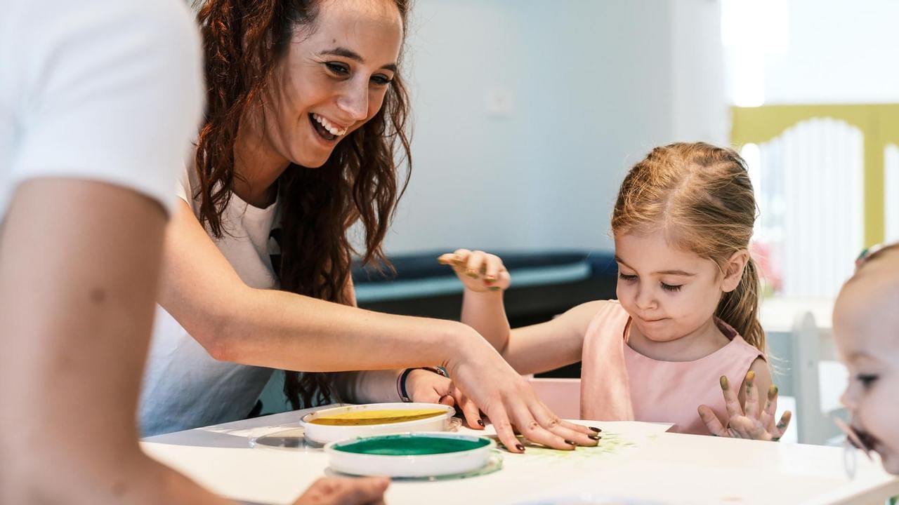 Adult and child engaging in a painting activity at Falkensteiner Family Hotel Diadora