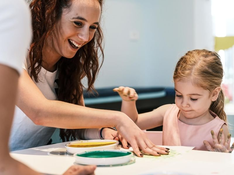 Adult and child engaging in a painting activity at Falkensteiner Family Hotel Diadora