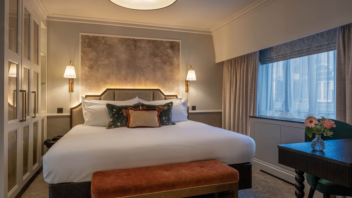 Bed with side tables and ottoman near window in Townhouse Junior Suite at The Capital Hotel, Apartments and Townhouse