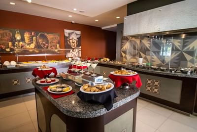 Pastries on an island by a buffet under a metal hood at Hotel Mirra, a hotel in San Luis Rio Colorado with restaurant and bar