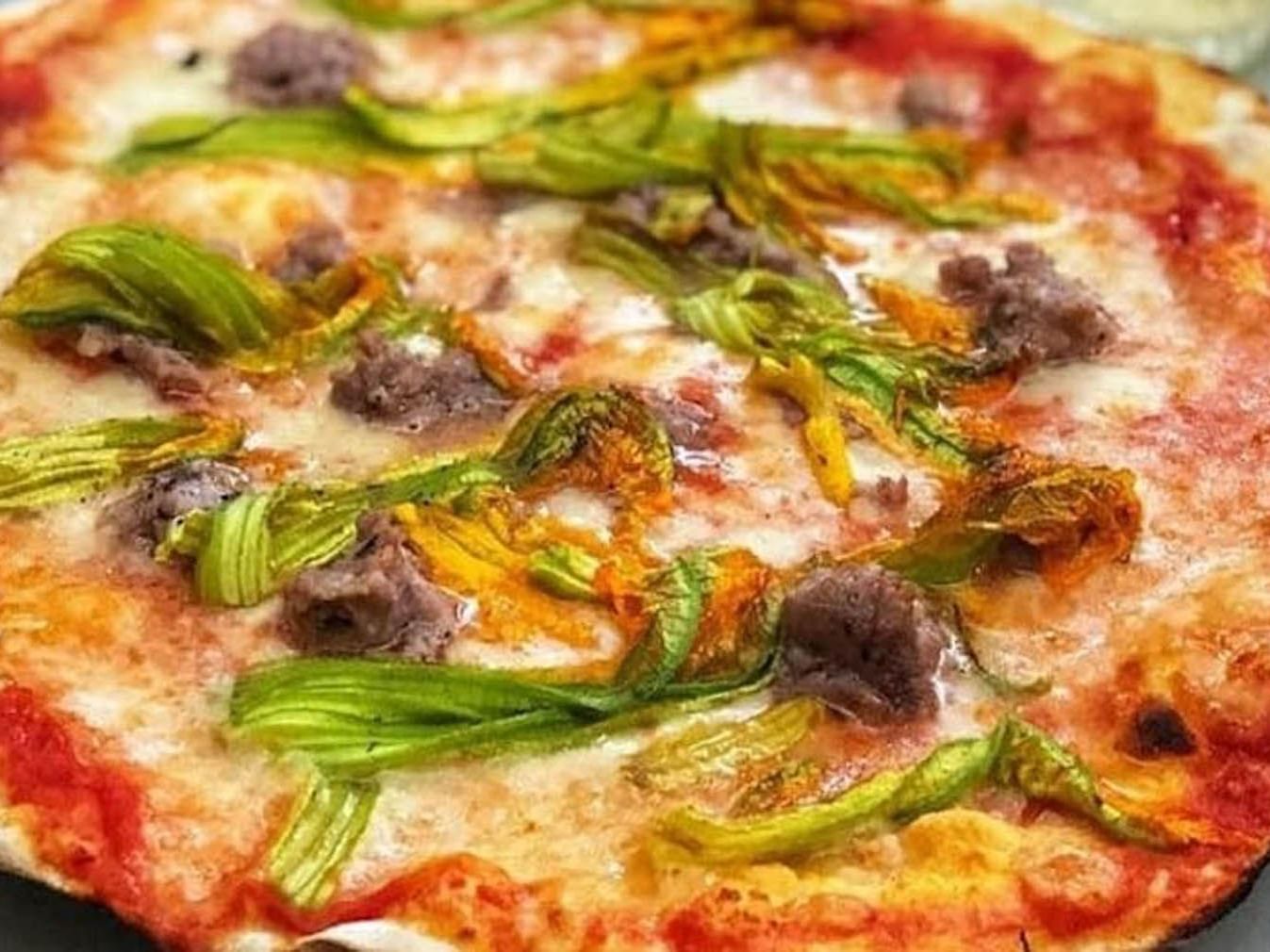 Close-up of a pizza topped with melted cheese, tomato sauce, and chunks of meat, freshly baked at The Guardian Hotel
