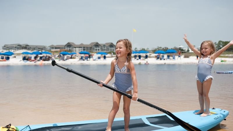 Close-up of two kids on a paddle board in the beach near Watersound Inn