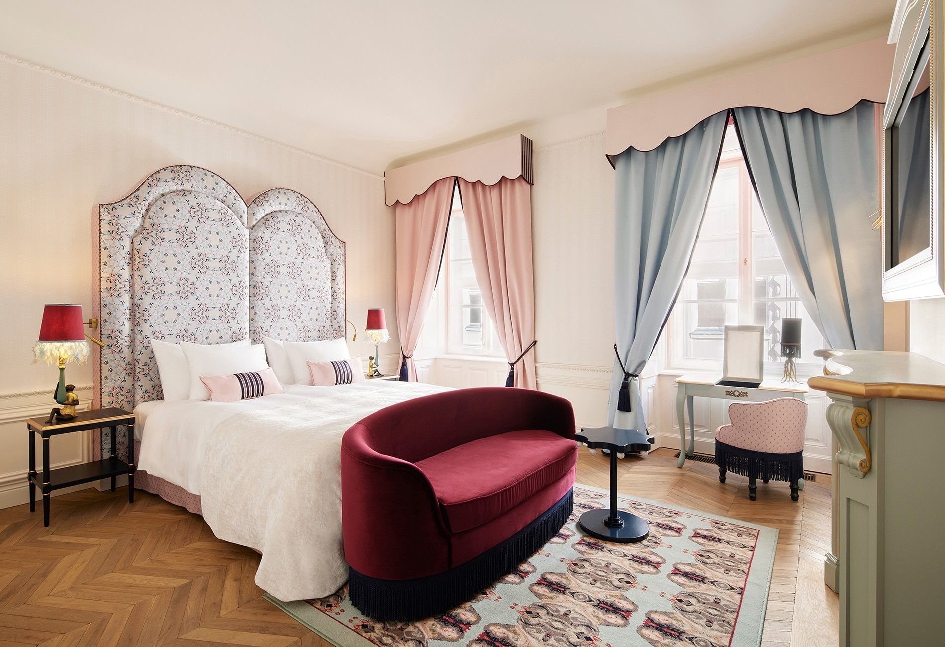 Grand Deluxe room at Hotel The Leo Grand featuring playful design, an elegant velvet sofa, and a floral headboard in pastel shades.