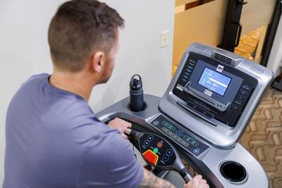 High angle view of a man using a digital treadmill console with water bottle in the fitness gym at Rodd Royalty
