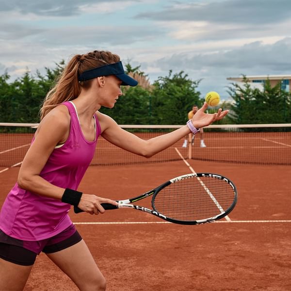 Woman playing tennis on a clay court near Falkensteiner Resort Punta Skala