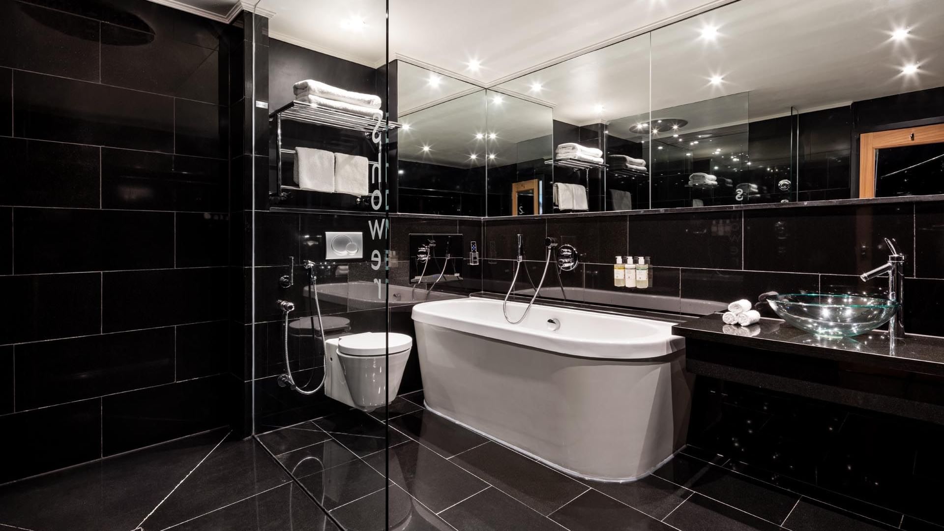 Sleek bathroom in The Saffron Suite at The May Fair Hotel London, featuring a bathtub, glass sink, and large mirror