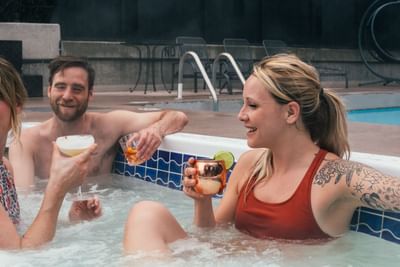 Friends enjoying cocktails in rooftop hot tub at Adara Hotel