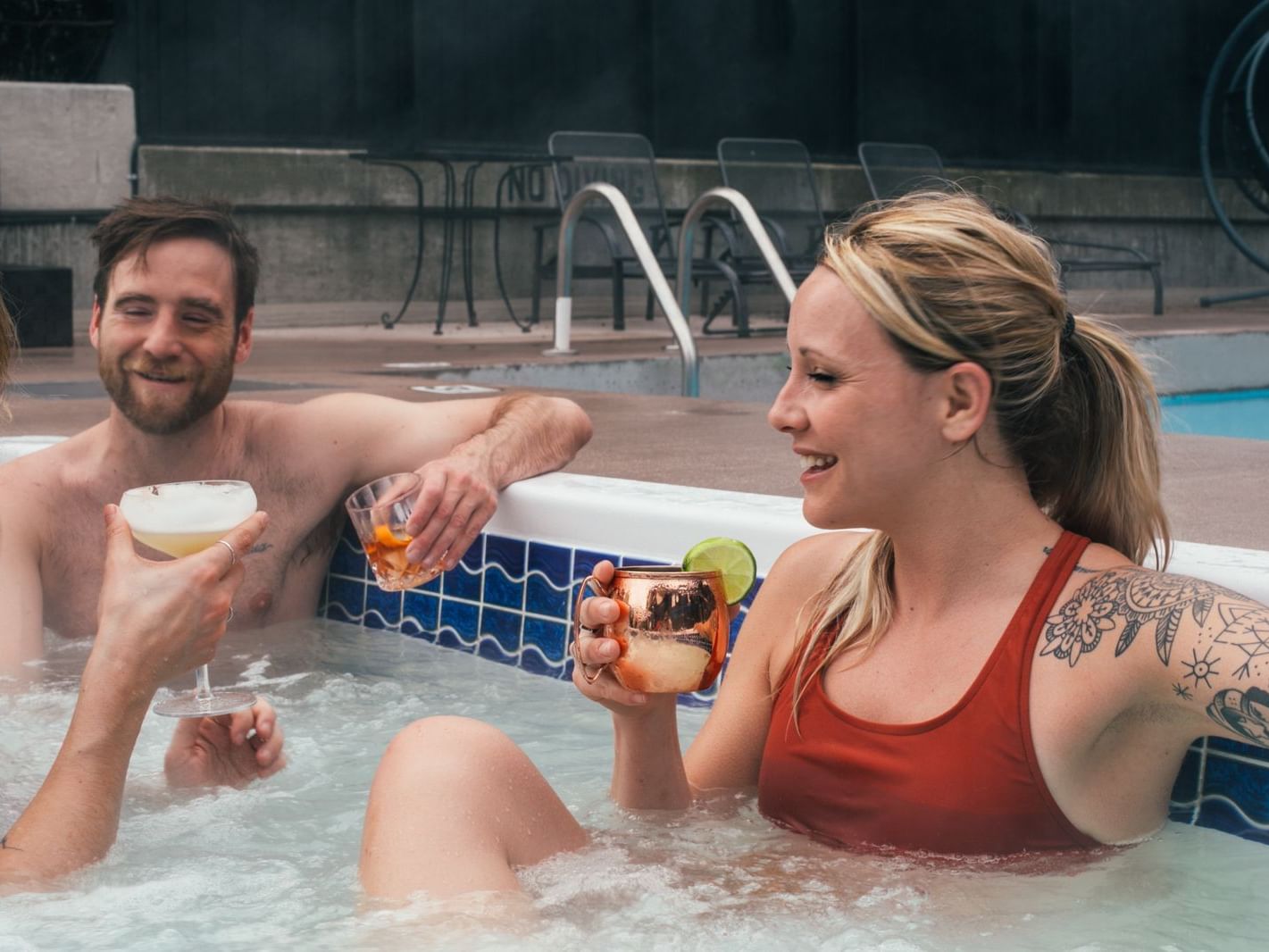 Friends in heated rooftop pool enjoying cocktails, Adara Hotel