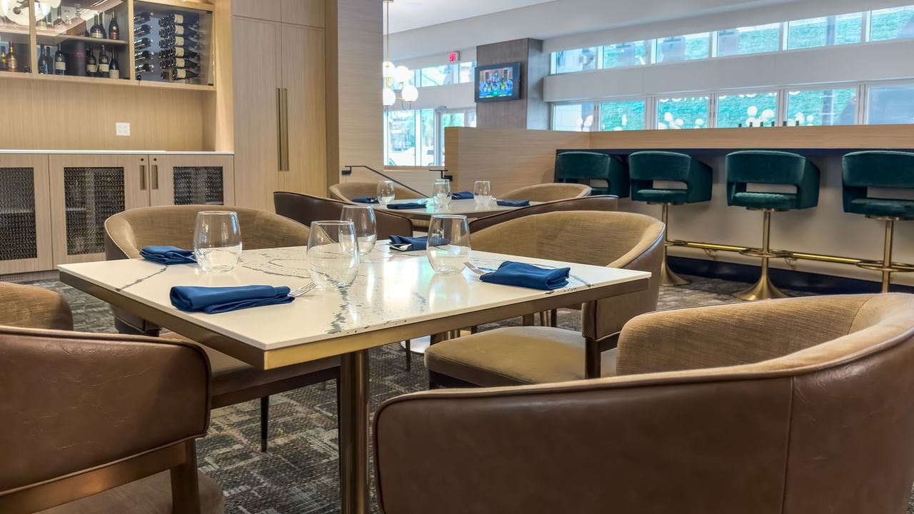 Restaurant dining area with set tables, chairs, and bar seating.