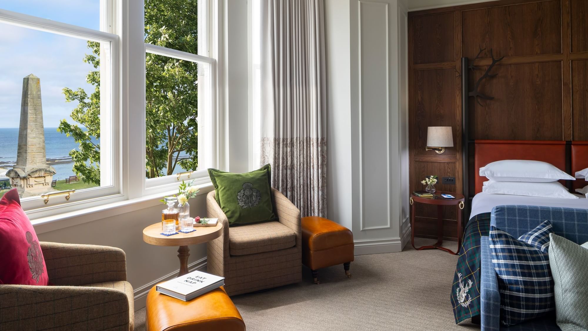Junior suite with sea view, with two armchairs, an ottoman, and a bed by a large window at Seaton House