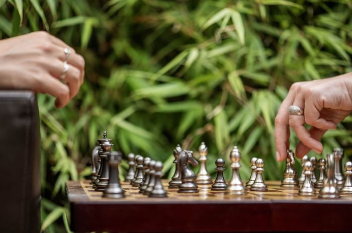 Two people playing chess with greenery in the background at Hotel Barsey by Warwick 