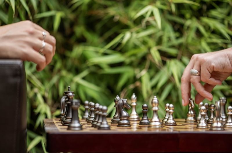 Close-up of guests playing a game of chess on a wooden board at the Hotel Barsey by Warwick