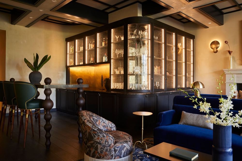 Sophisticated bar with illuminated display cases, comfortable seating, and elegant decor at El Prado Hotel
