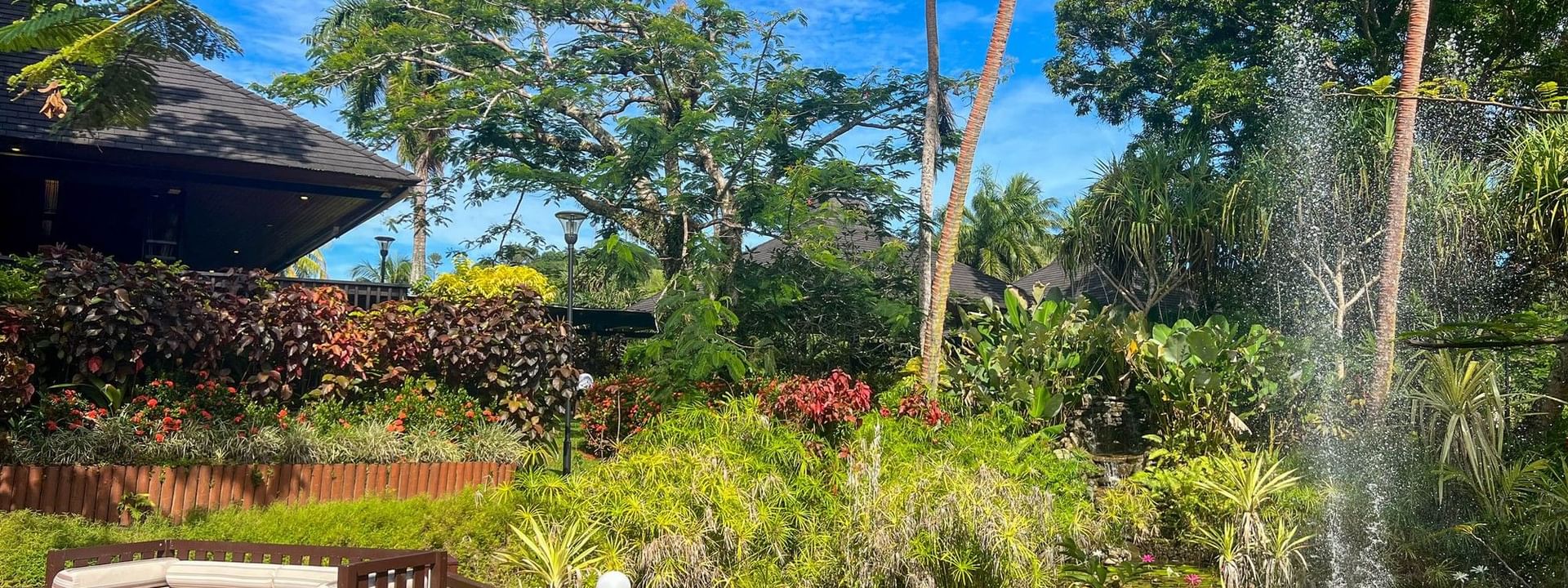 Serene wooden deck with a bench overlooking lush gardens and a fountain at The Naviti Resort in Korolevu