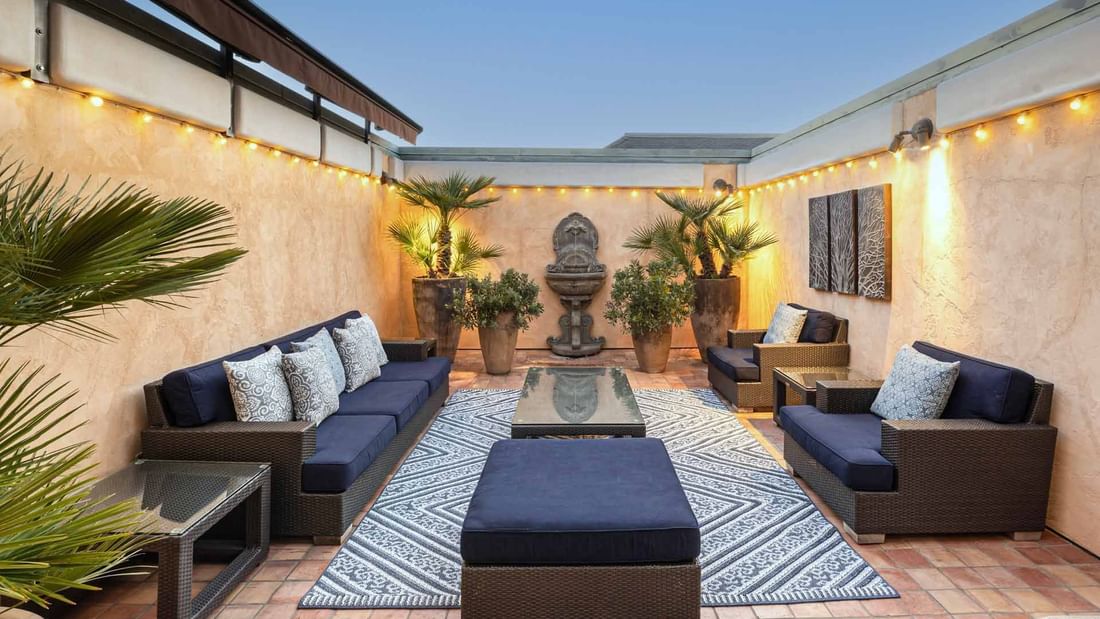 Penthouse patio at El Prado Hotel featuring cozy seating, string lights, and lush greenery for a relaxed ambiance