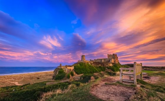 An ancient castle facing the sea during a sunset