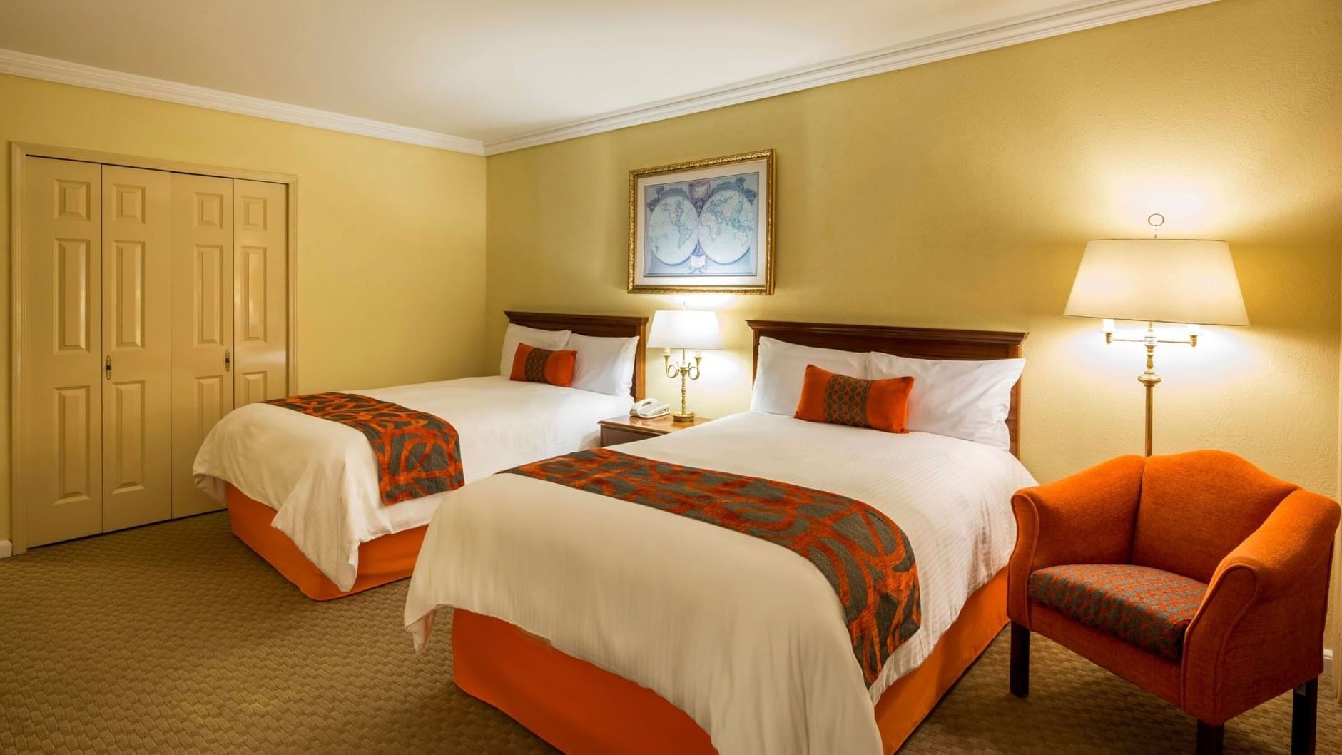 Two queen beds in 2 Double Deluxe with vibrant orange accents and a comfortable side chair at Camino Real Puebla Angelopolis