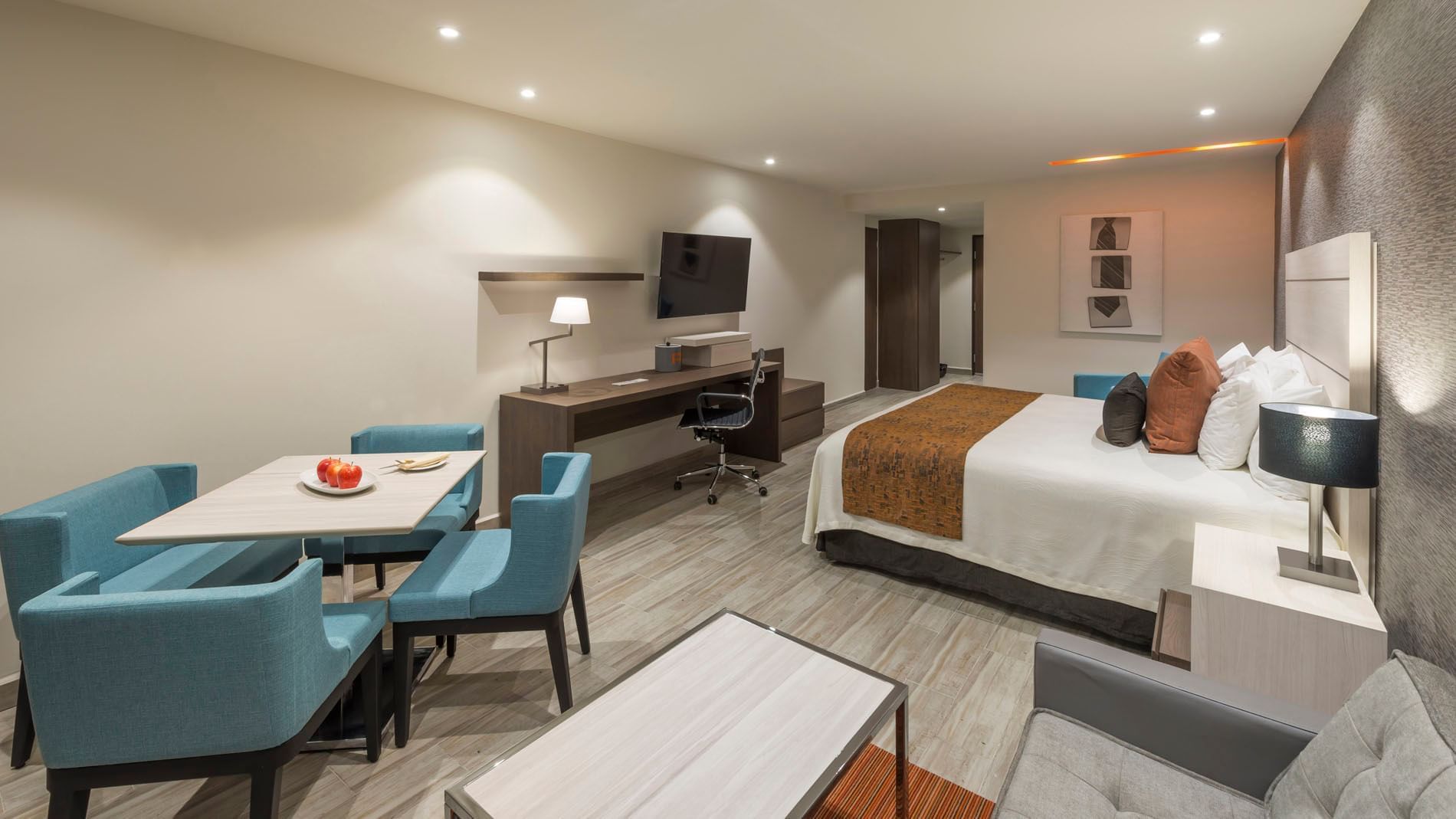 King Superior room with a dining table, blue chairs, and a wall-mounted TV over a long desk at Real Inn Celaya