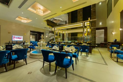 Taki Sushi Restaurant with blue velvet chairs by a multi-tiered fountain in Taki Restaurant at Warwick Al Khobar