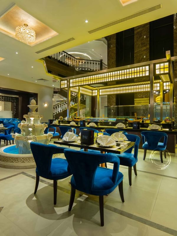 Taki Sushi Restaurant with blue velvet chairs by a multi-tiered fountain in Taki Restaurant at Warwick Al Khobar