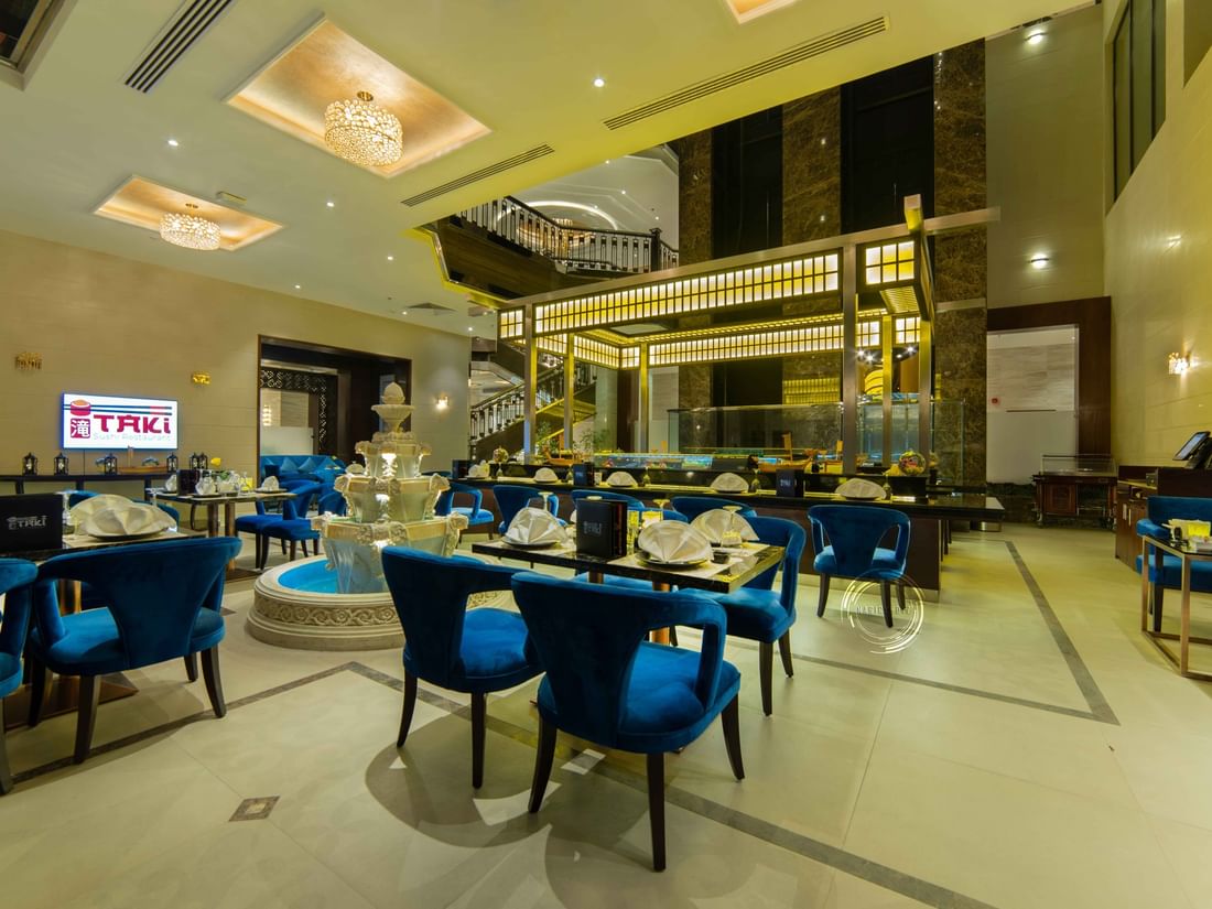 Taki Sushi Restaurant with blue velvet chairs by a multi-tiered fountain in Taki Restaurant at Warwick Al Khobar
