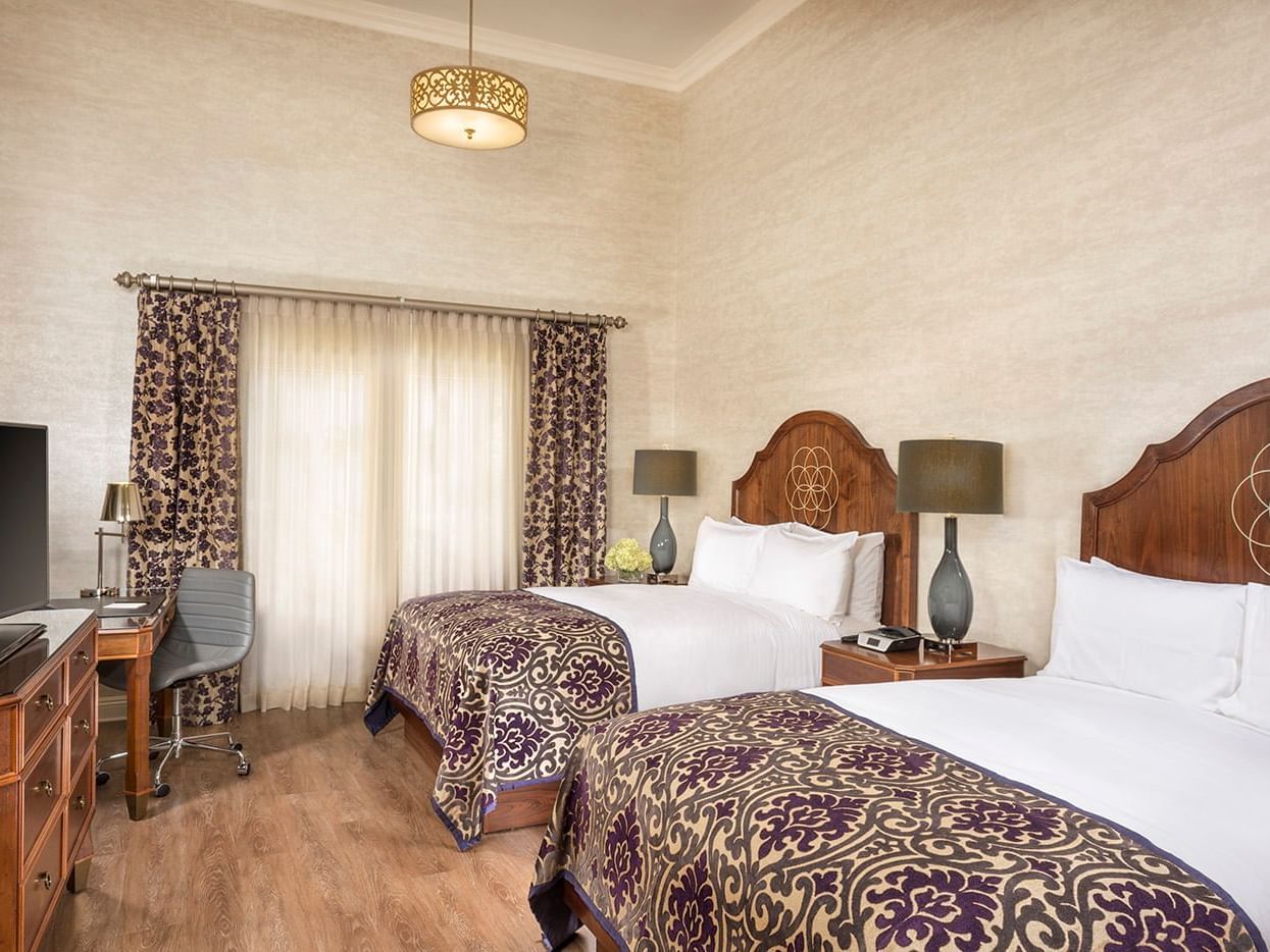 A room which includes Two queen size beds, a writing desk and a flat screen TV.
