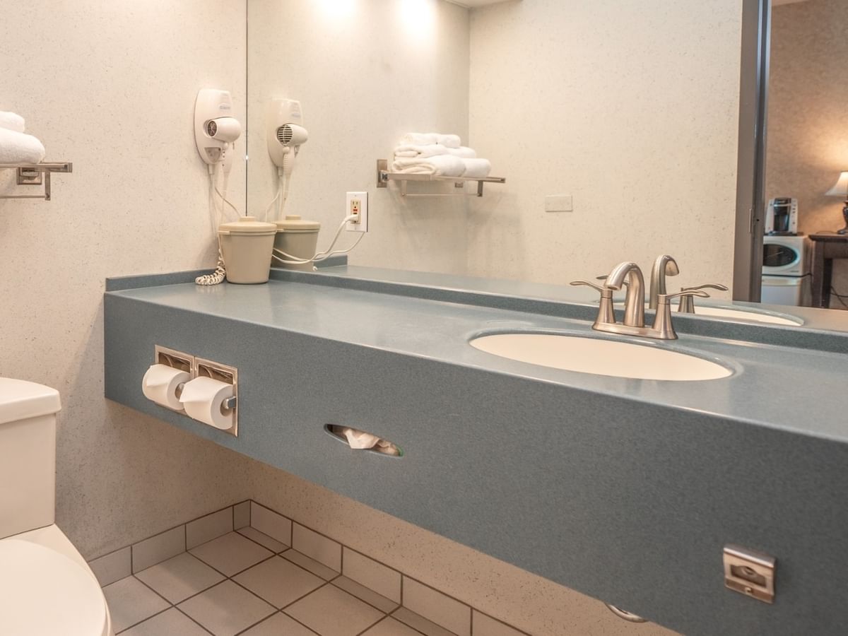Coast Queen bathroom with toilet, vanity, sink, mirror, towels, and hair dryer at Coast Lonsdale Quay Hotel