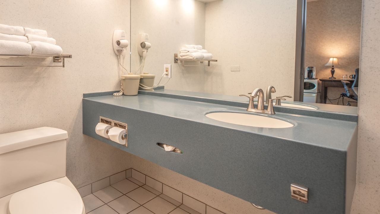 Coast Queen bathroom with toilet, vanity, sink, mirror, towels, and hair dryer at Coast Lonsdale Quay Hotel