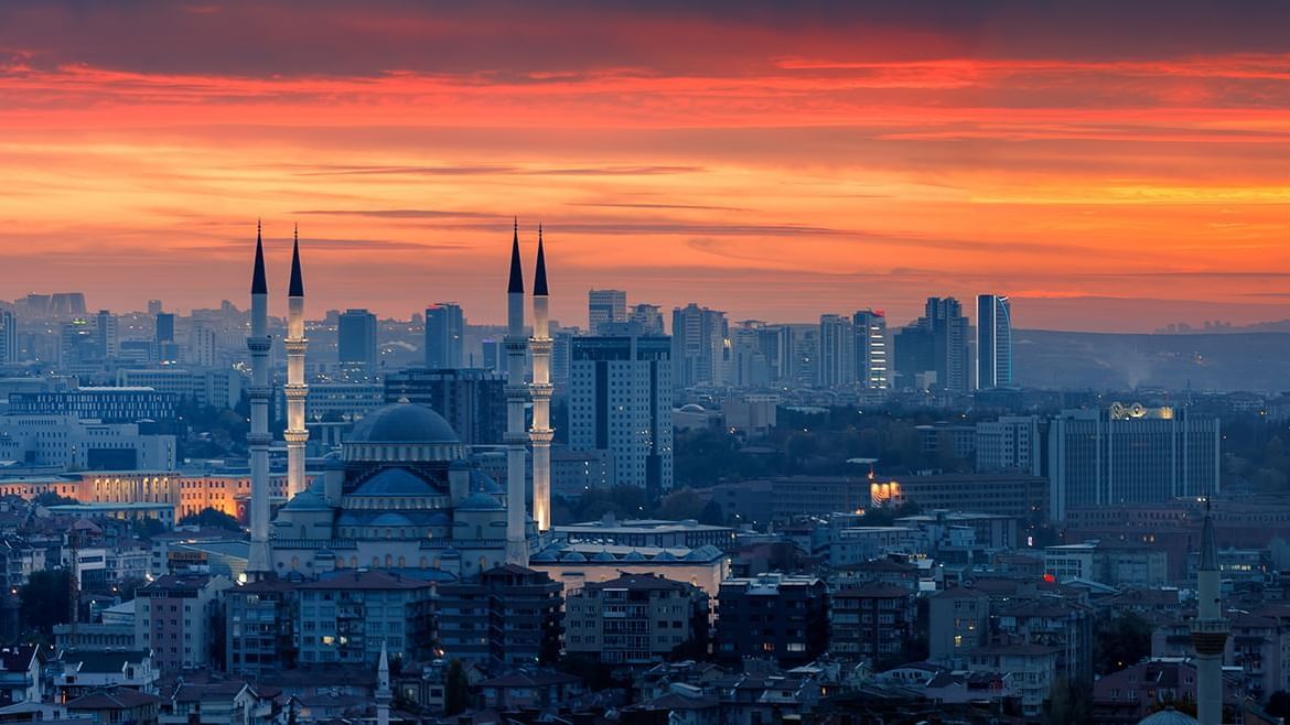 A panoramic view of a city at sunset, featuring a Ankara mosquee with tall minarets near Warwick Hotels and Resorts