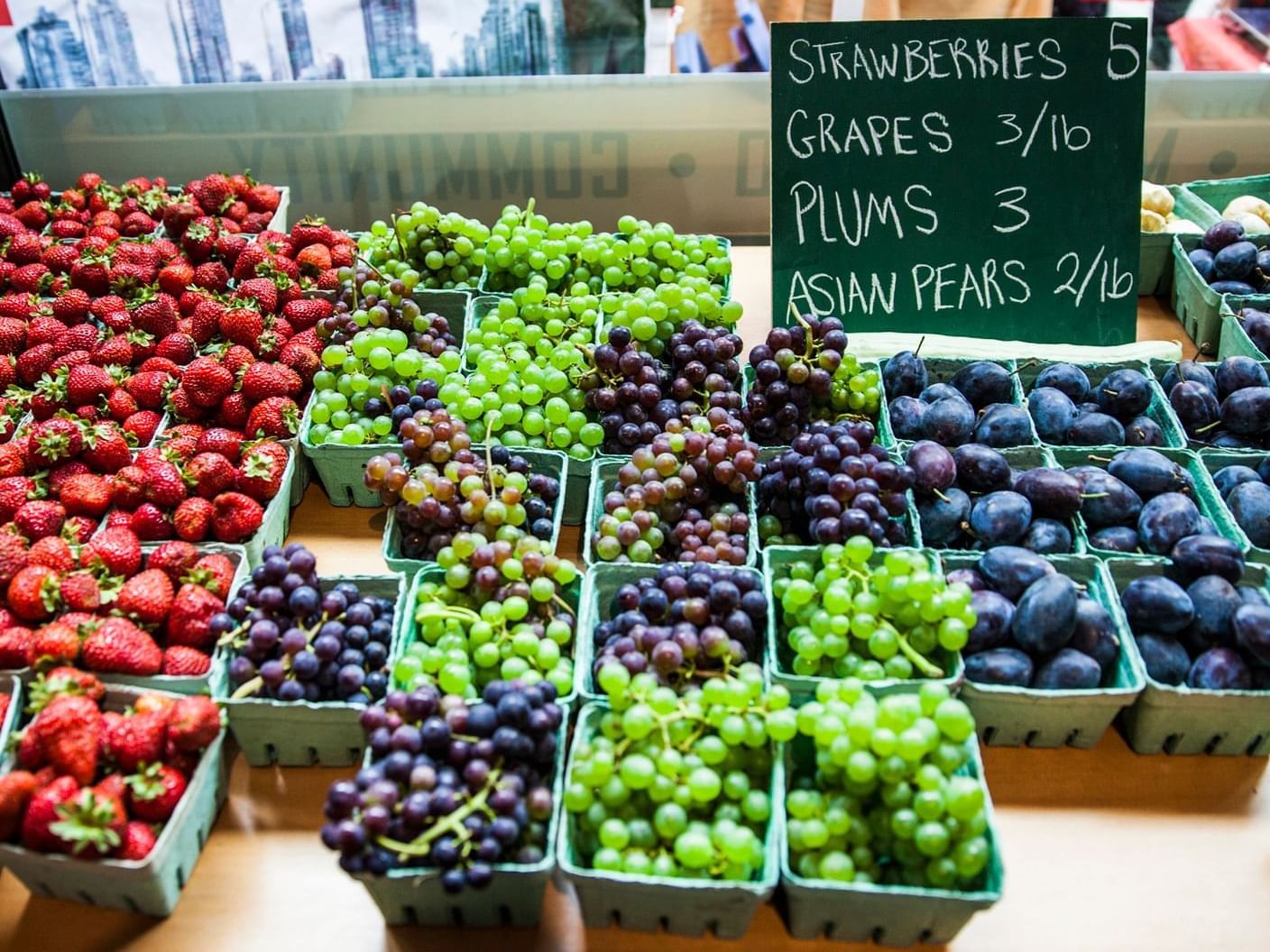 Assortment of fresh grapes & berries by a board with prices in Huntingdon Manor