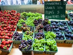 Assortment of fresh grapes & berries by a board with prices in Huntingdon Manor