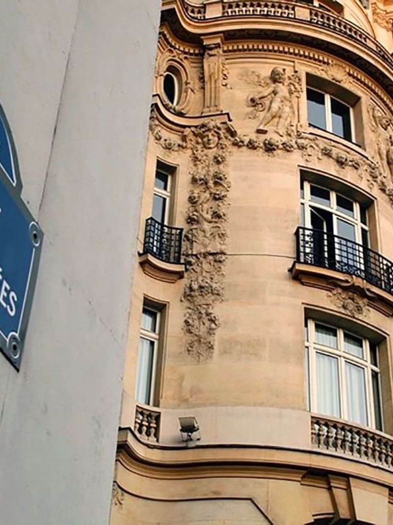 Champs-Élysées by an ornate stone building under windows near Warwick Paris Champs Elysées