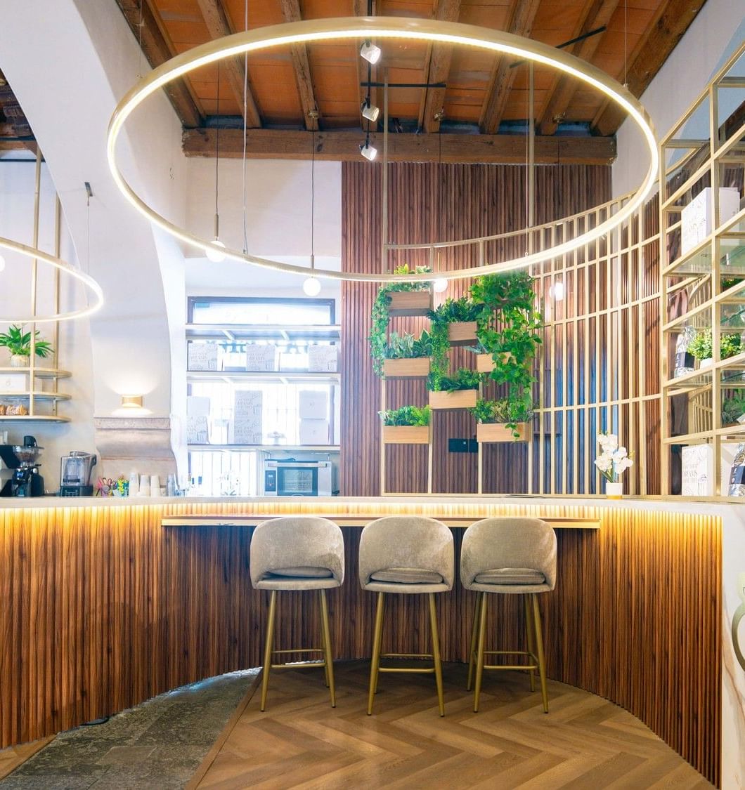 Mostrador de café con paneles de madera verticales y luces circulares de halo en Quinta Real Puebla