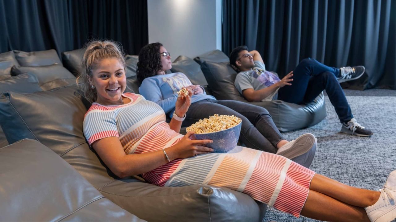 Residents lounging on beanbag chairs, with one woman holding a bowl of popcorn.