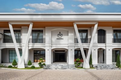 Exterior view of the hotel facade and motor lobby on a sunny day at Amora Hotel