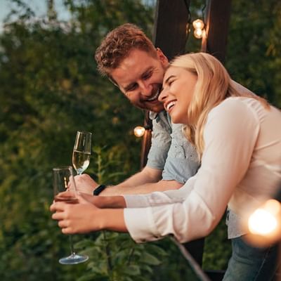 A couple enjoying champagne on a balcony at Originals Hotels