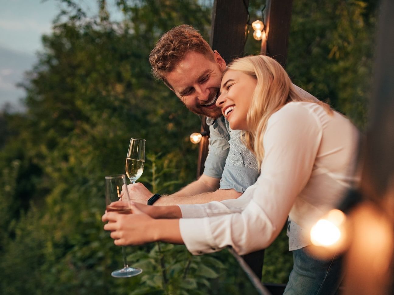 A couple enjoying champagne on a balcony at Originals Hotels