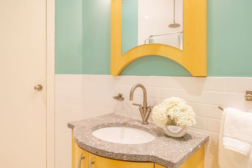 a bright blue bathroom with a yellow trim mirror and sink in sun