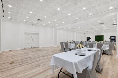Elegant ballroom at The Riverwalk Plaza Hotel with white tables, chairs, floral displays, bright lighting, and modern decor