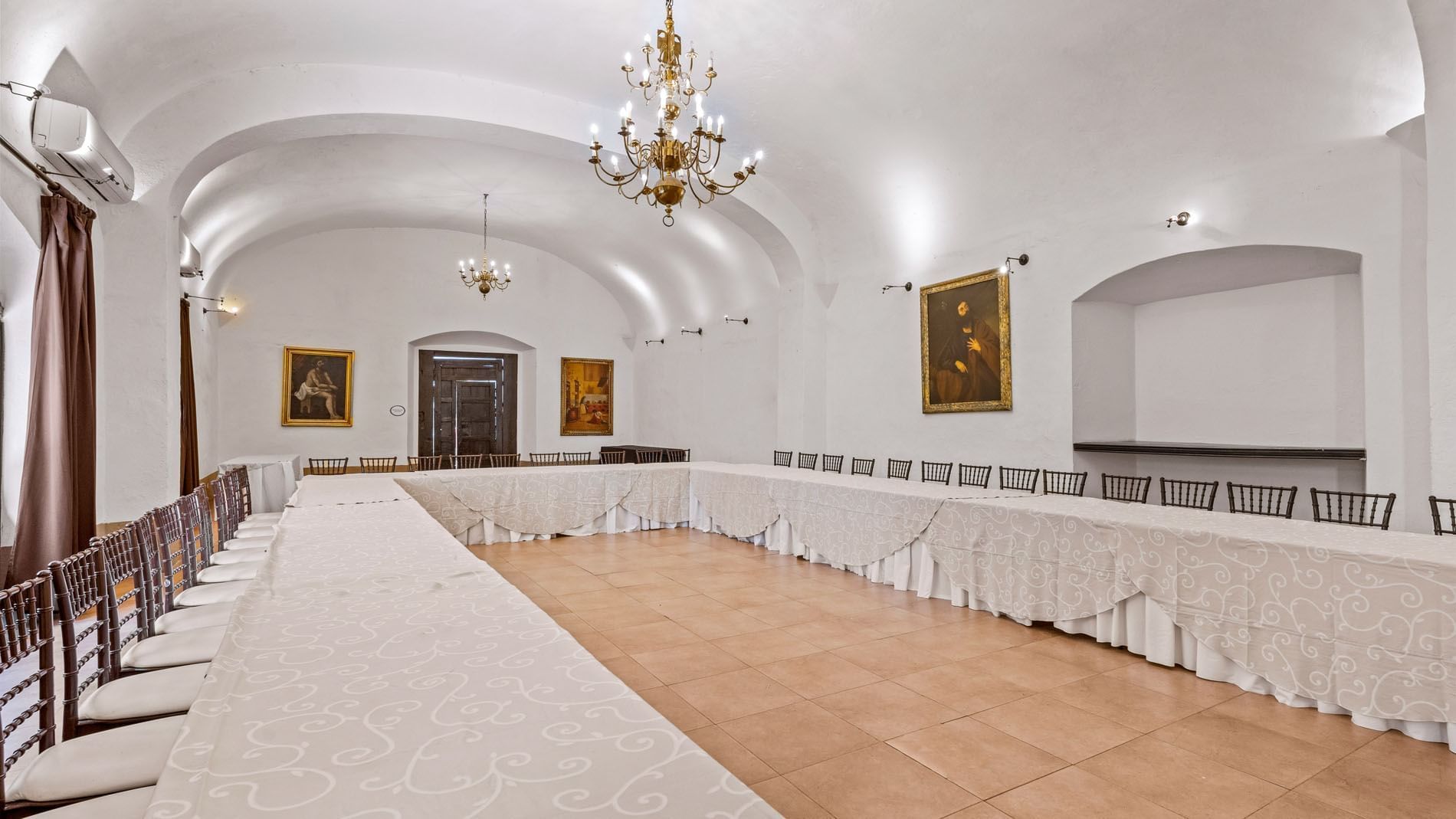 Formal meeting room with vaulted ceilings, religious paintings, and a long white table in Cholula at Quinta Real Puebla