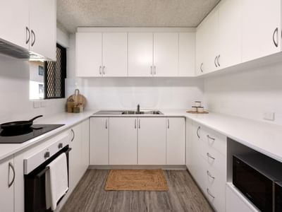 Modern white kitchen with appliances and wooden floors at UniLodge at Curtin University - Guild House.