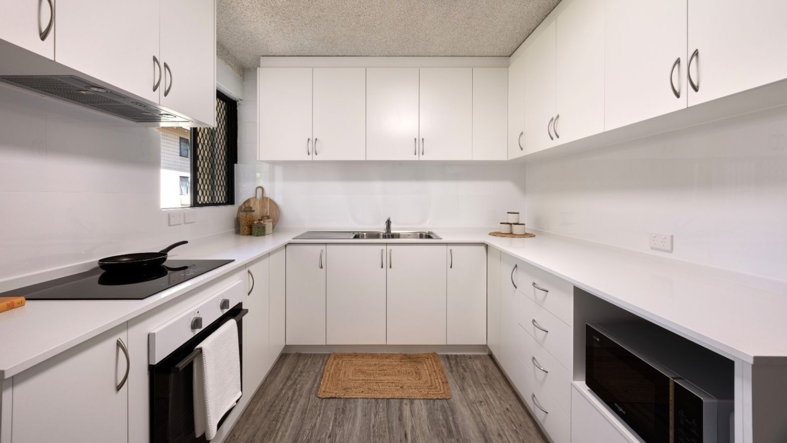 Modern white kitchen with appliances and wooden floors at UniLodge at Curtin University - Guild House.