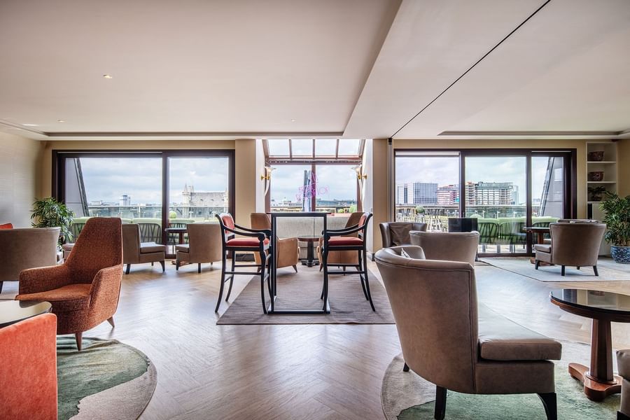 Ruime lounge met comfortabele zithoeken en panoramische ramen met uitzicht op de stad bij Warwick Brussels Grand-Place