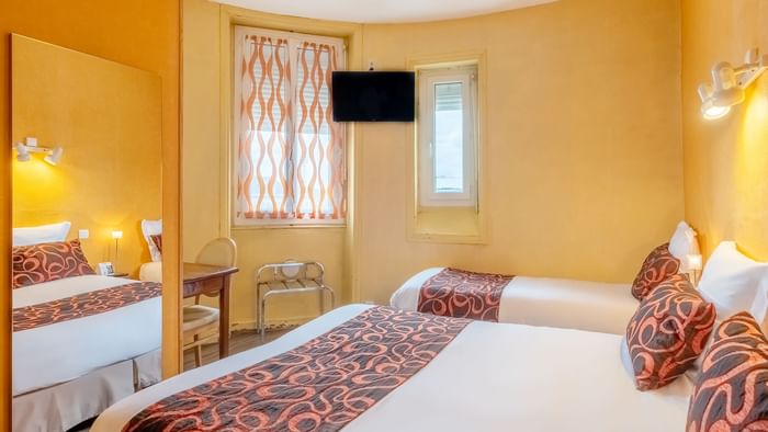 3-person bedroom with comfy beds & a TV at The Originals Hotels