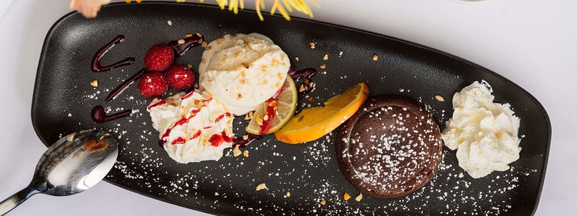 Chocolate fondant and vanilla ice cream on a black plate by a coffee cup in Téséo at Warwick Geneva