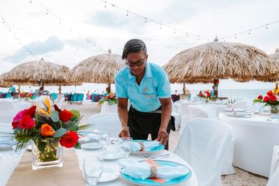 Waiter arranging the dining tables by the shore at Passions on the Beach