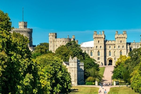 Windsor Castle surrounded by greenery under a clear sky.